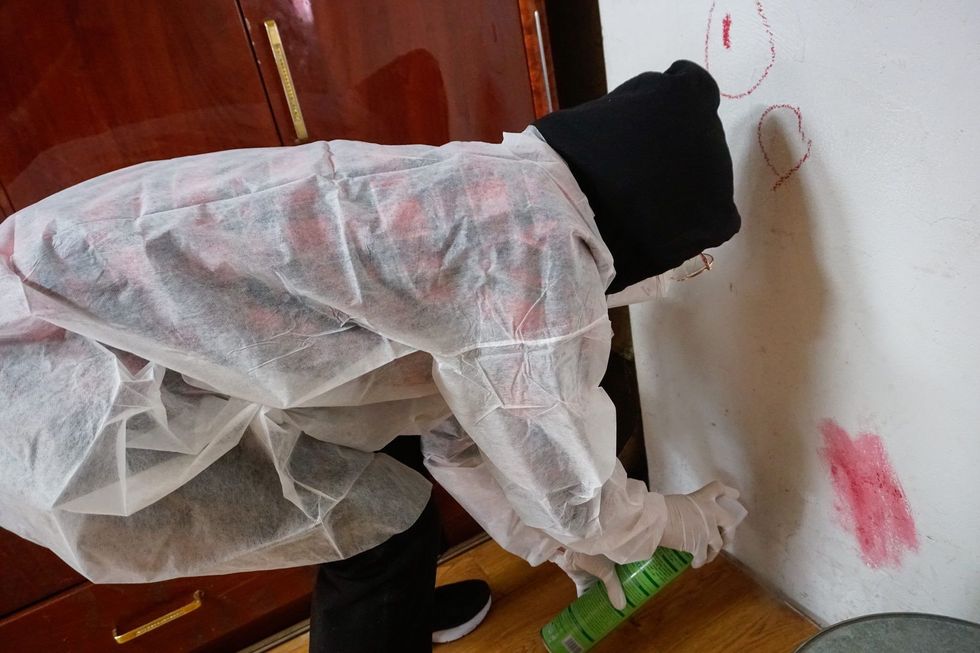 Dressed in personal protective equipment, Oyuka sprays insecticides inside her home in Erdenet, Orkhon province.
