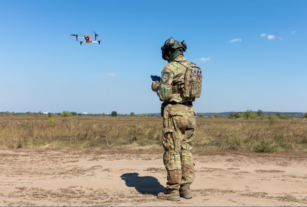 Drone operator launches a quadcopter to monitor the operation of an evacuation robot during its field testing