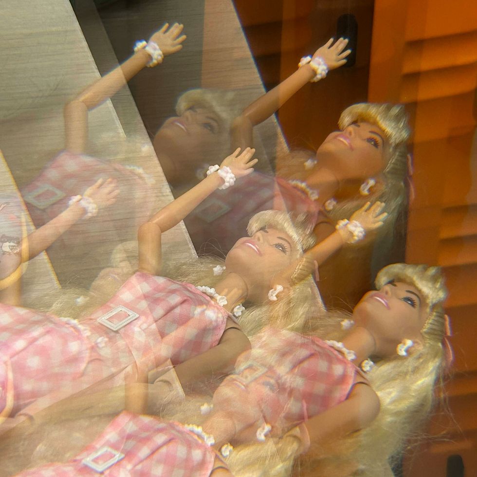 ​A barbie dressed in pink and white.