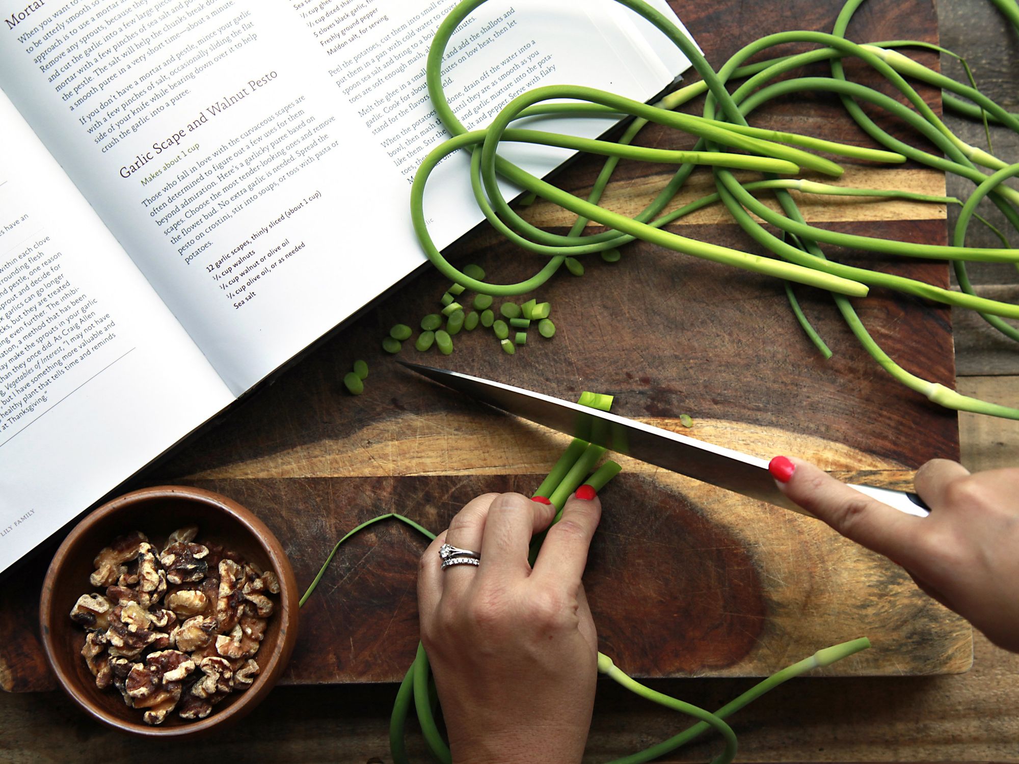​A chef chopping green onion next to a recipe from a cookbook.