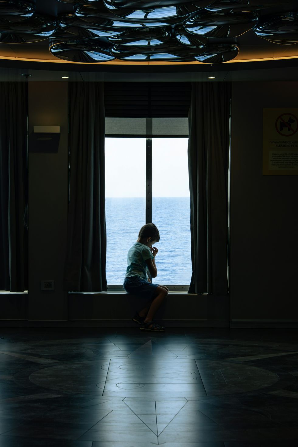 ​A child sitting on a window sill looking out at the ocean, Kefalonia, Cephalonia, Greece, Sept. 19, 2024.