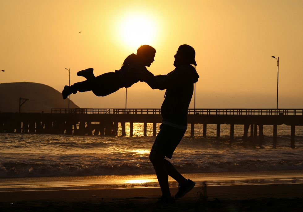 ​A father and son playing on the beach.
