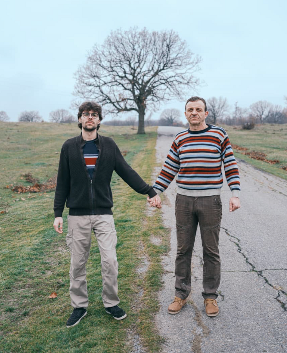 ​A father holding hands with his adult son.