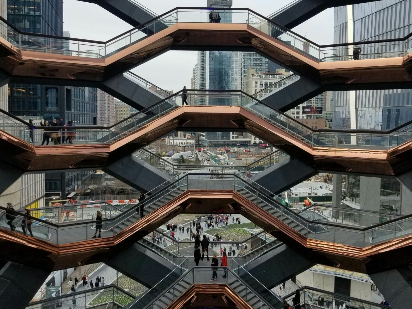 ​A group of people walking around The Vessel in New York City.
