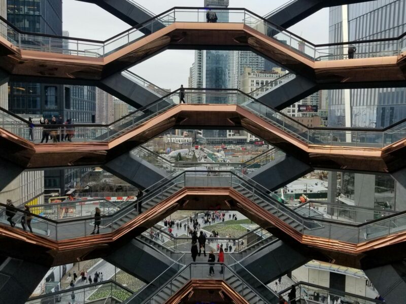 ​A group of people walking around The Vessel in New York City.
