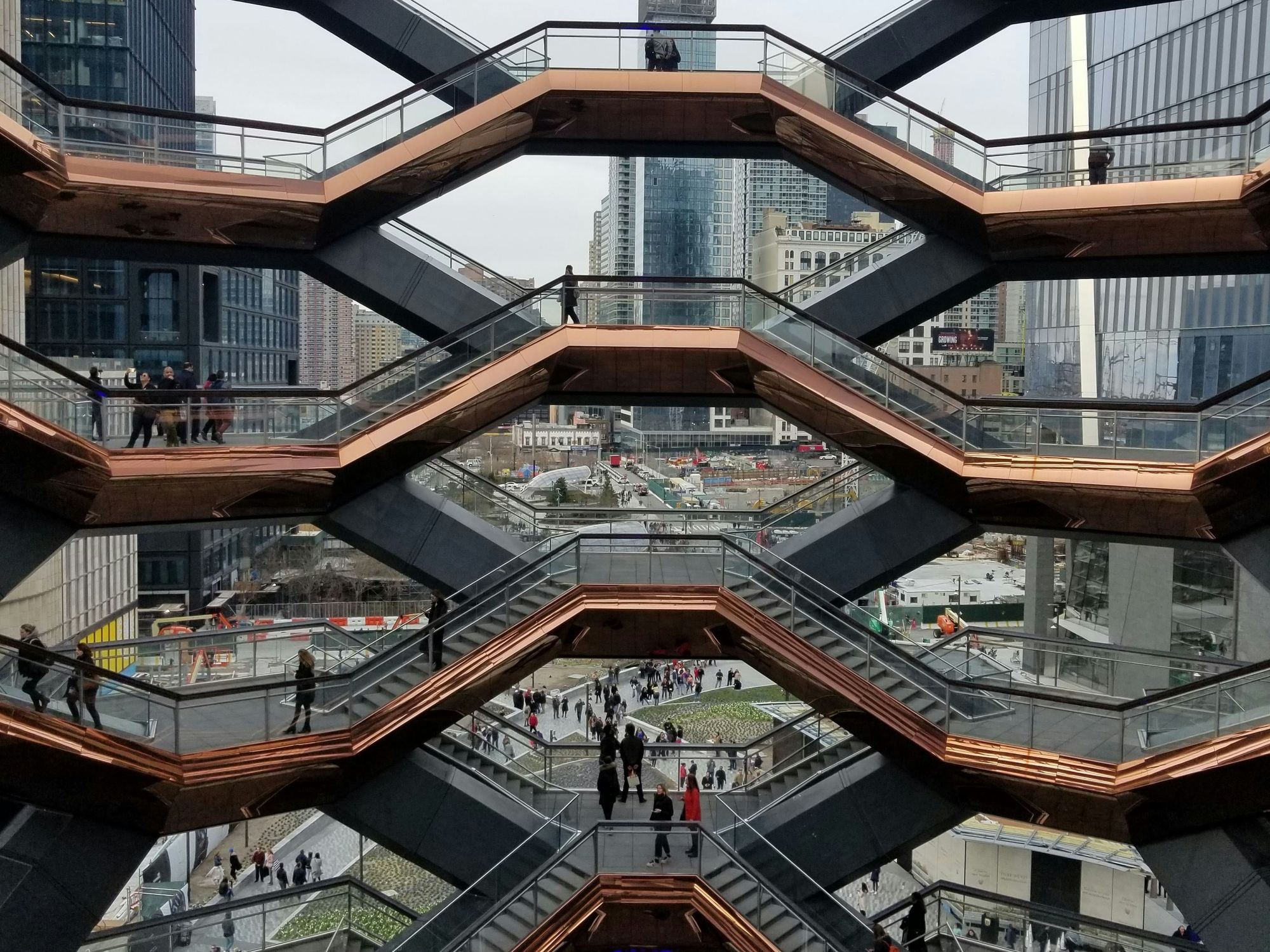 ​A group of people walking around The Vessel in New York City.