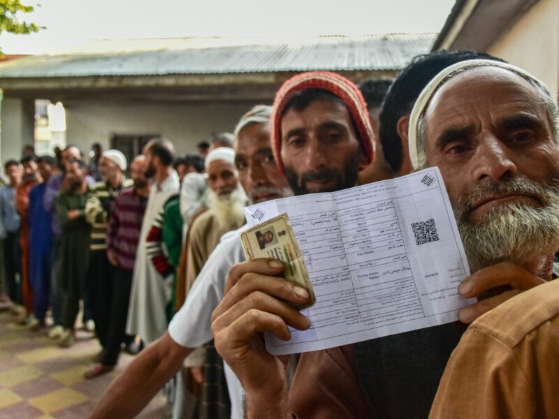 ​A Kashmiri man shows his voter slip as he lines up to cast his ballot at a polling station, during the first phase of assembly elections, in Pulwama, India, Sept. 18, 2024.