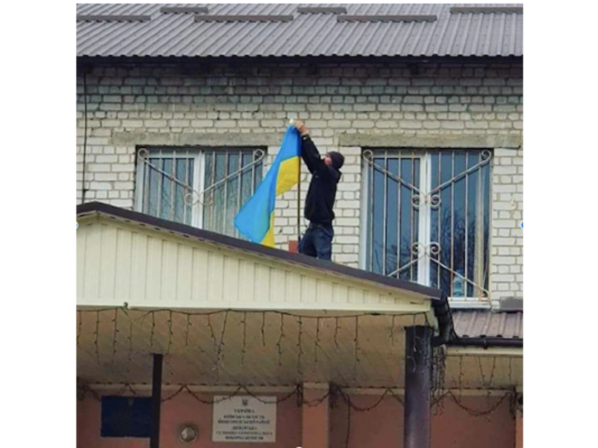 ​A man putting the Ukrainian flag on a roof in support of Ukraine