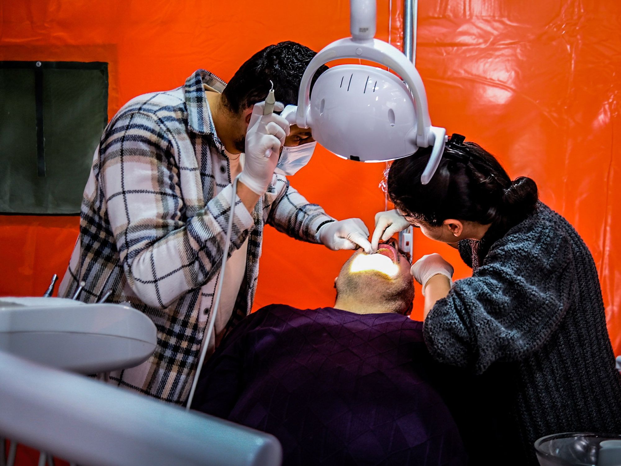 ​A man receives treatment in a dentist's tent.