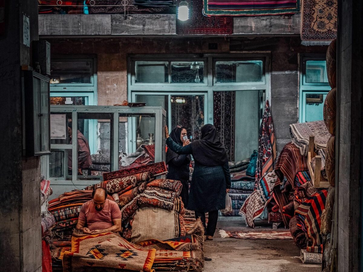 ​A man repairs a carpet in Tehran