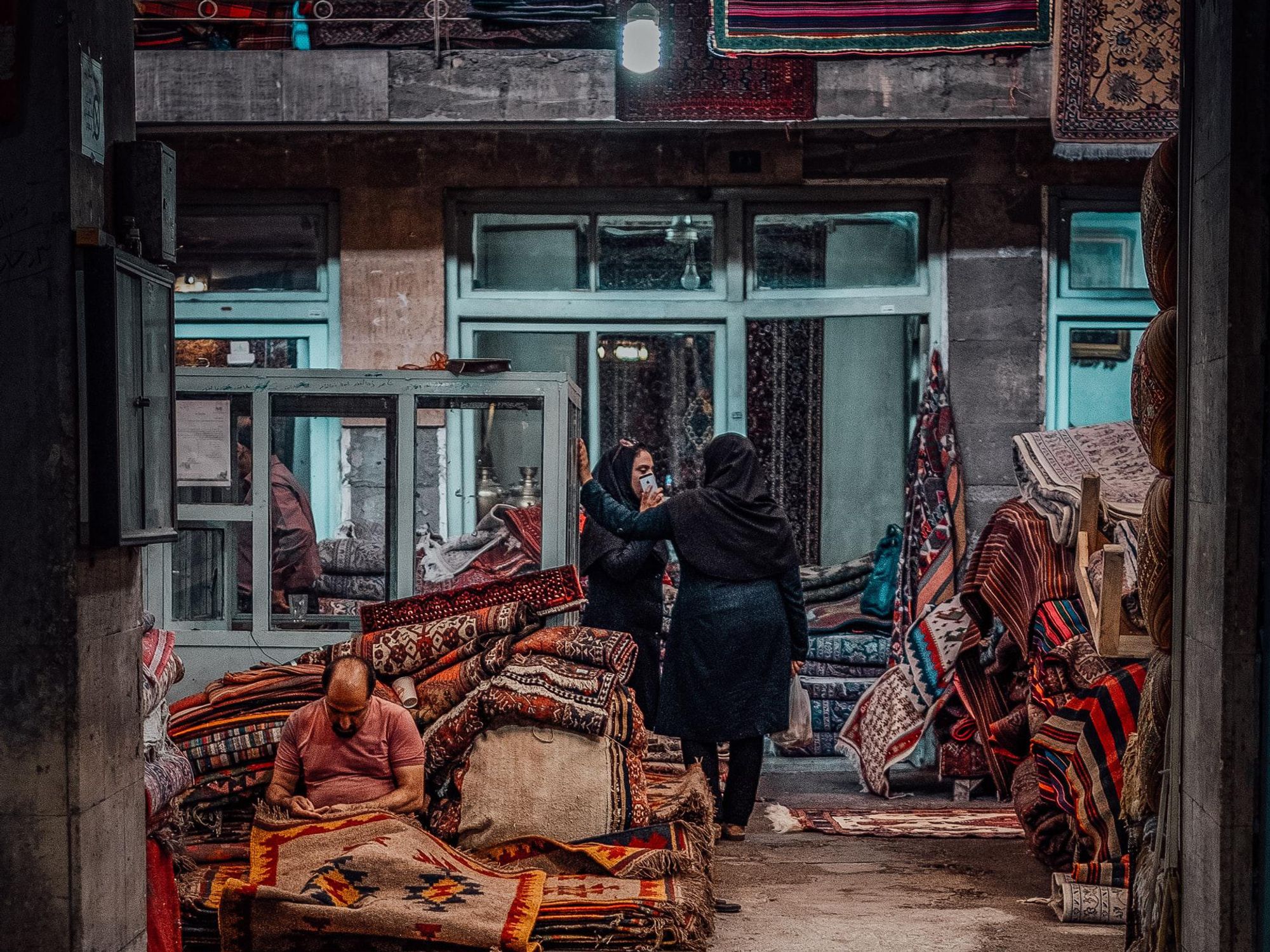 ​A man repairs a carpet in Tehran