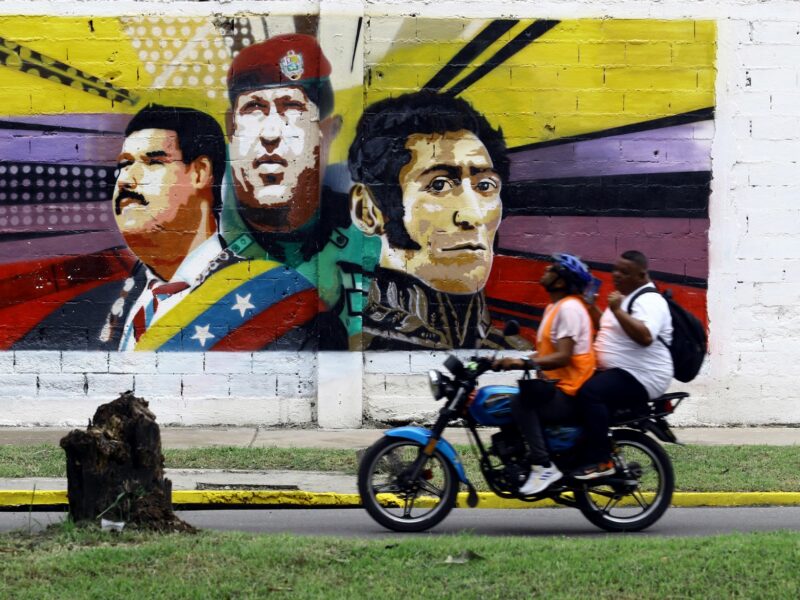 ​A motorized vehicle passes in front of a grafitti with the image of the president of Venezuela, Nicolas Maduro.