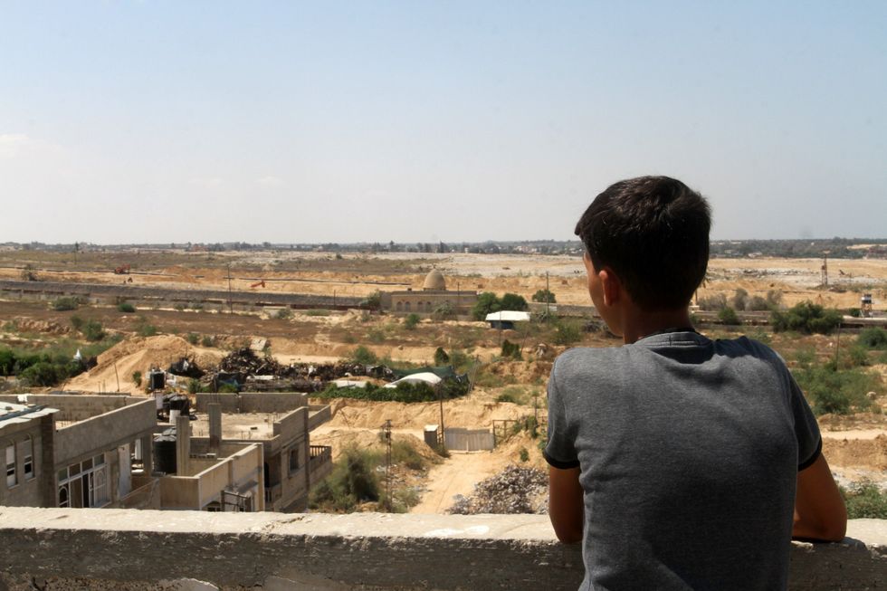 ​A Palestinian boy looks on as bulldozers and diggers working.