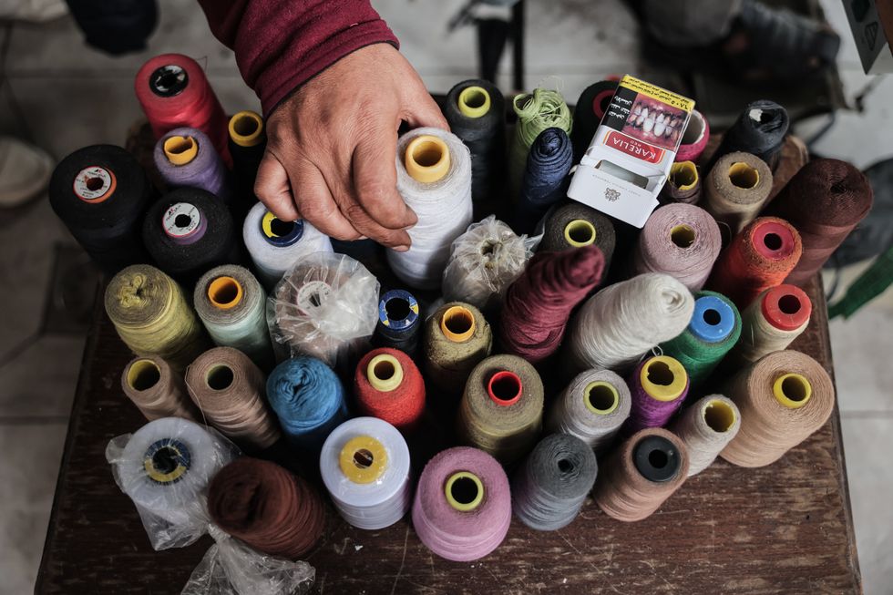 ​A Palestinian tailor showing the materials he works with while repairing.