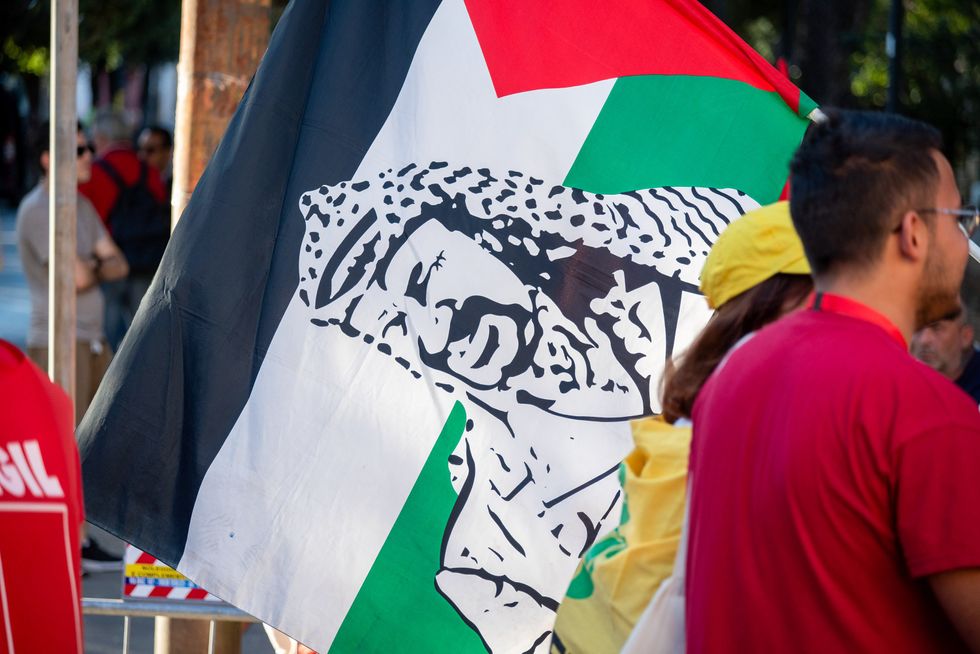 ​A protester holds a Palestinian flag with Yasser Arafat's portrait on it during the demonstration.