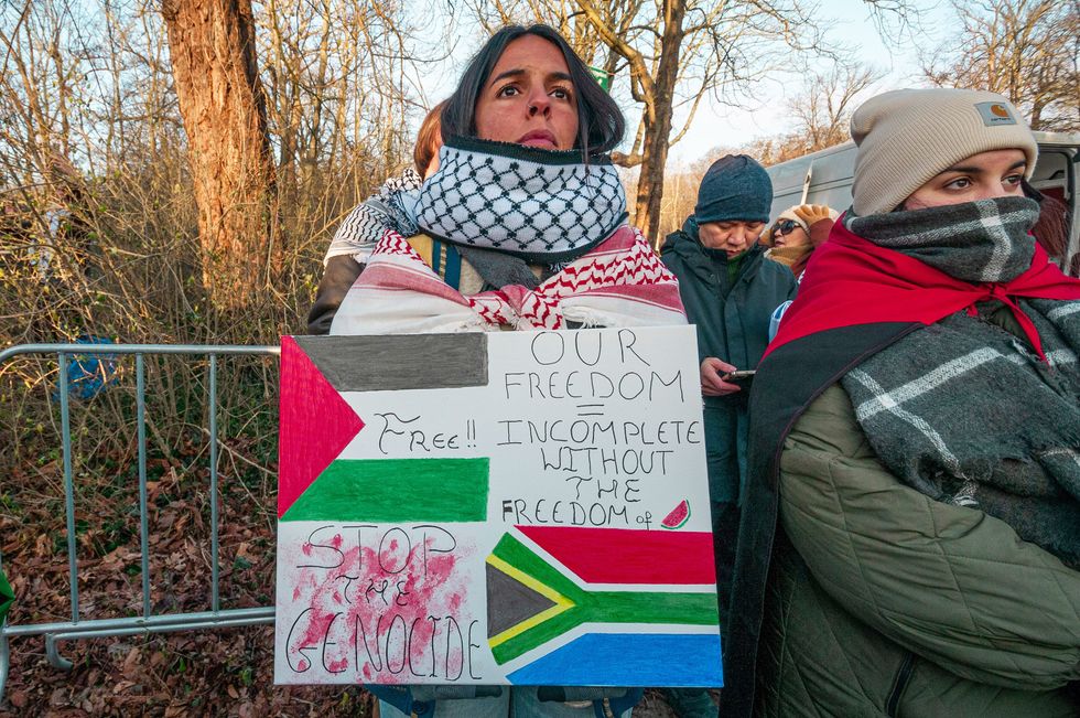 ​A protester holds a placard with "Our Freedom = Incomplete without the freedom of (watermelon)" with the Palestine flag and South Africa flag without during the ICJ hearing.