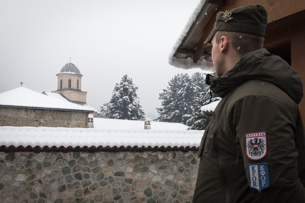 ​A soldier stands guard at the entrance to the Decani monastery in Kosovo.