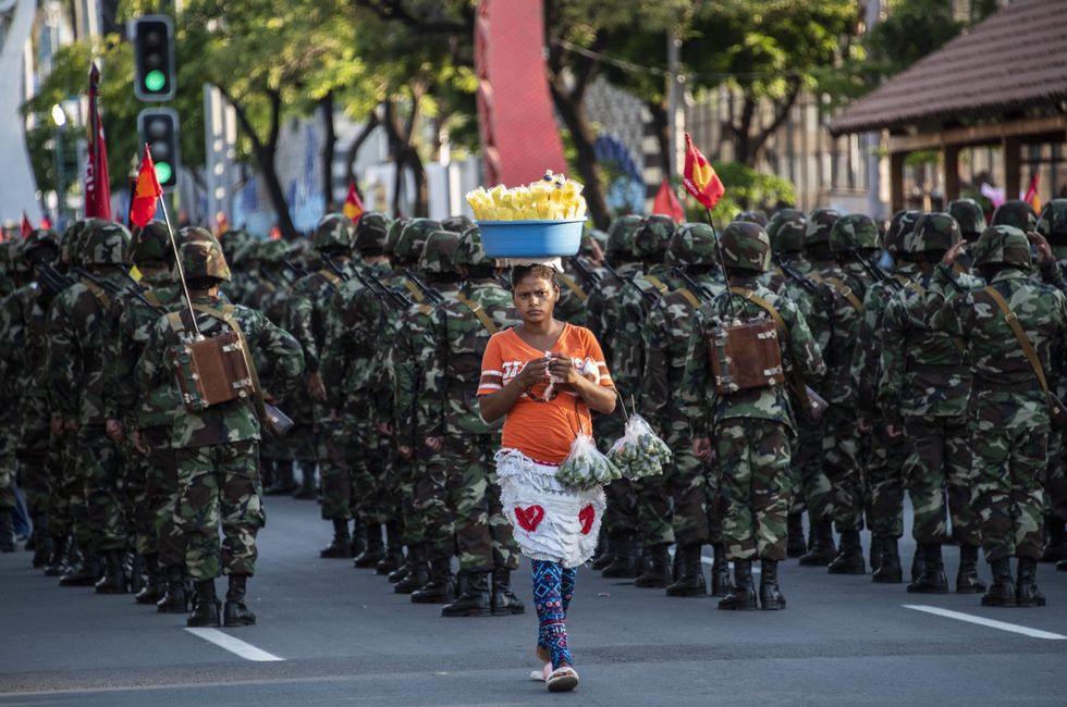 ​A street vendor walks past Nicaraguan Army soldiers preparing to participate in a military parade in Managua.