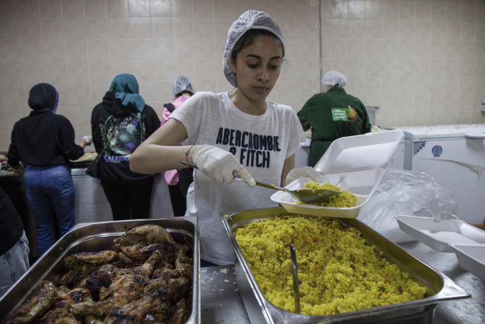 ​A volunteer of the Egyptian Food Bank prepares food boxes for Iftar at the bank kitchen before their distribution to poor people during the holy month of Ramadan.