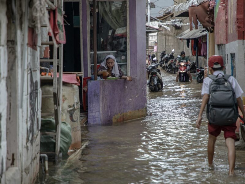 ​A woman eating breakfast during a flood in Jakarta, Indonesia, on Dec. 3, 2024.