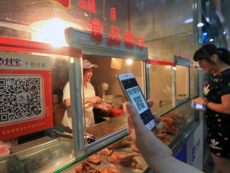 ​A woman scans the QR code by cellphone to pay for her purchases at a market in Wenzhou, China.