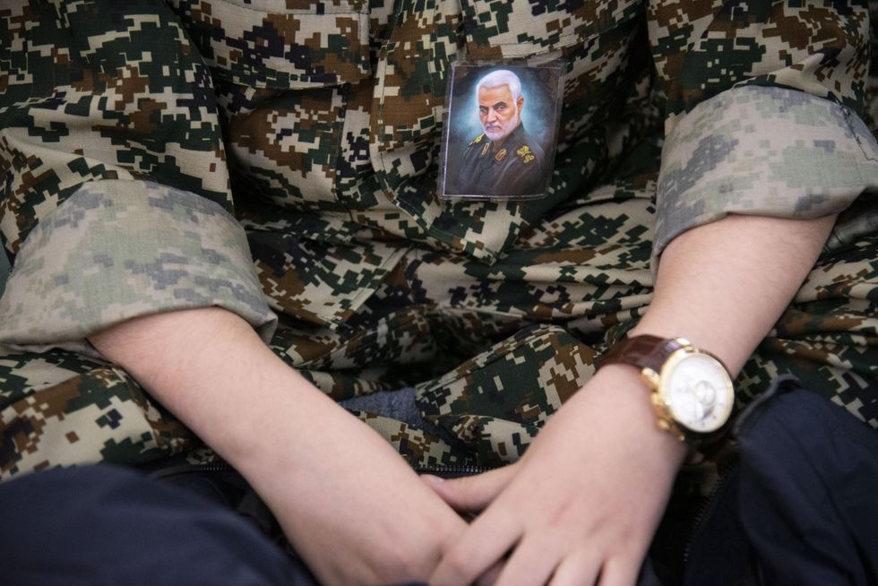 ​A young boy wearing an IRGC uniform and portrait of Qasem Soleimani