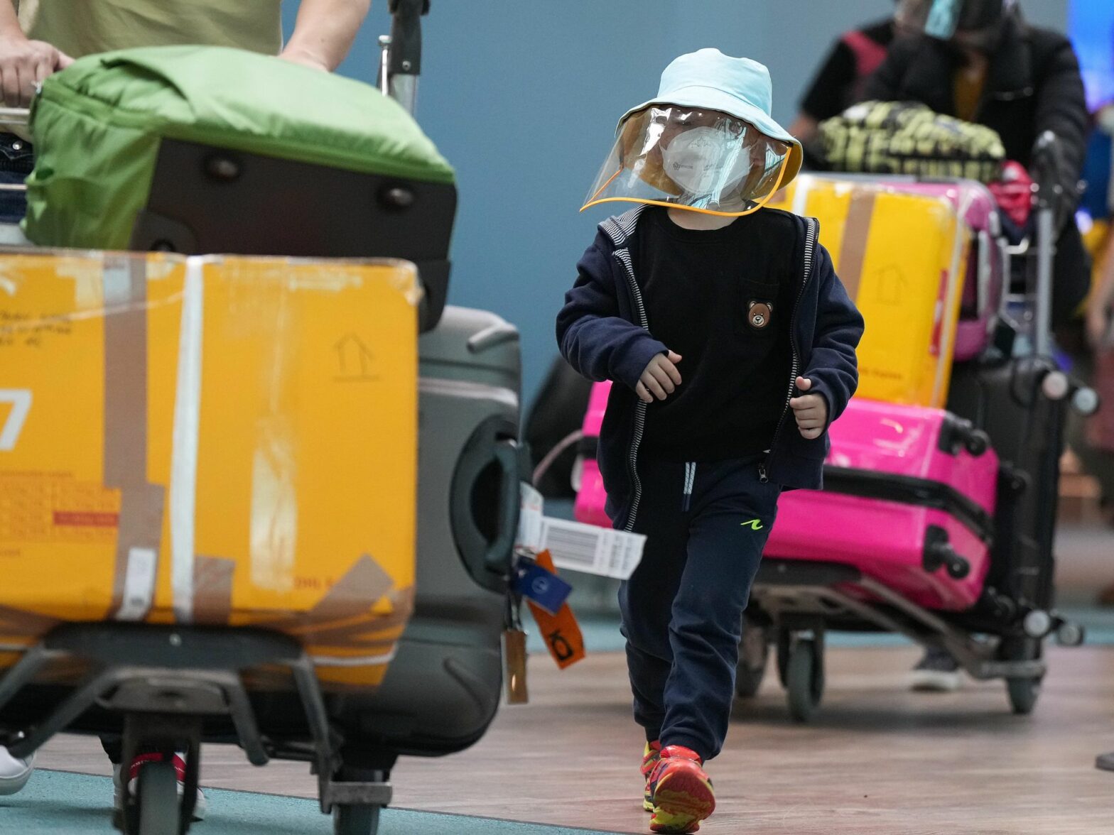 ​A young boy who arrived on a Cathay Pacific flight from Hong Kong wears a face mask and face shield at Vancouver International Airport in Canada on Jan. 10, 2023.