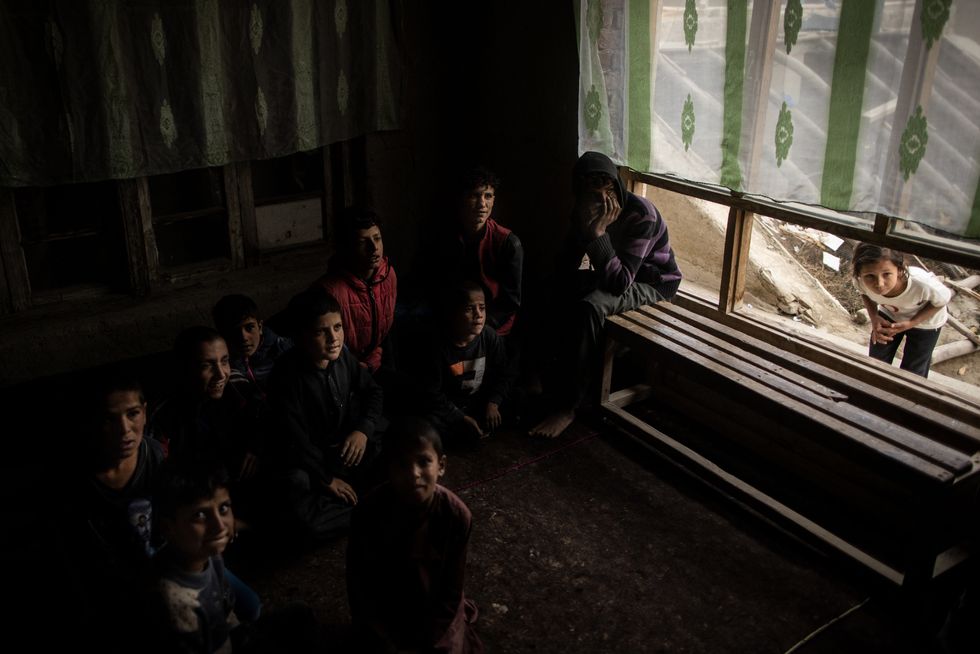 ​A young girl peeks into the classroom where young Afghan boys attend a lesson in Kabul, Afghanistan, Nov. 6, 2022.