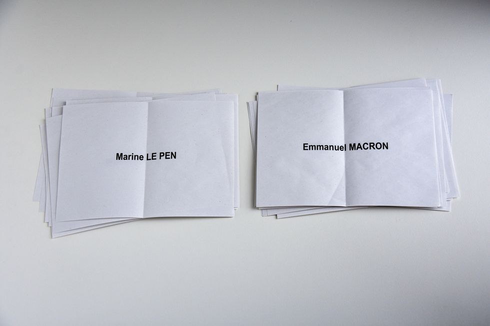 ​Ballot papers of Marine Le Pen and Emmanuel Macron displayed on a table.