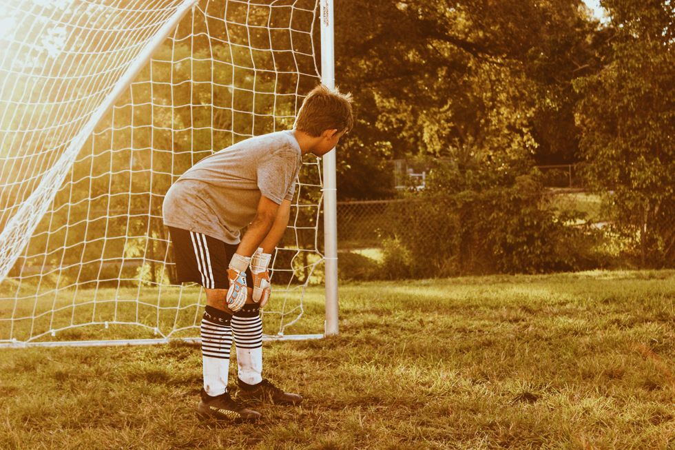 ​Boy standing on football goal net.