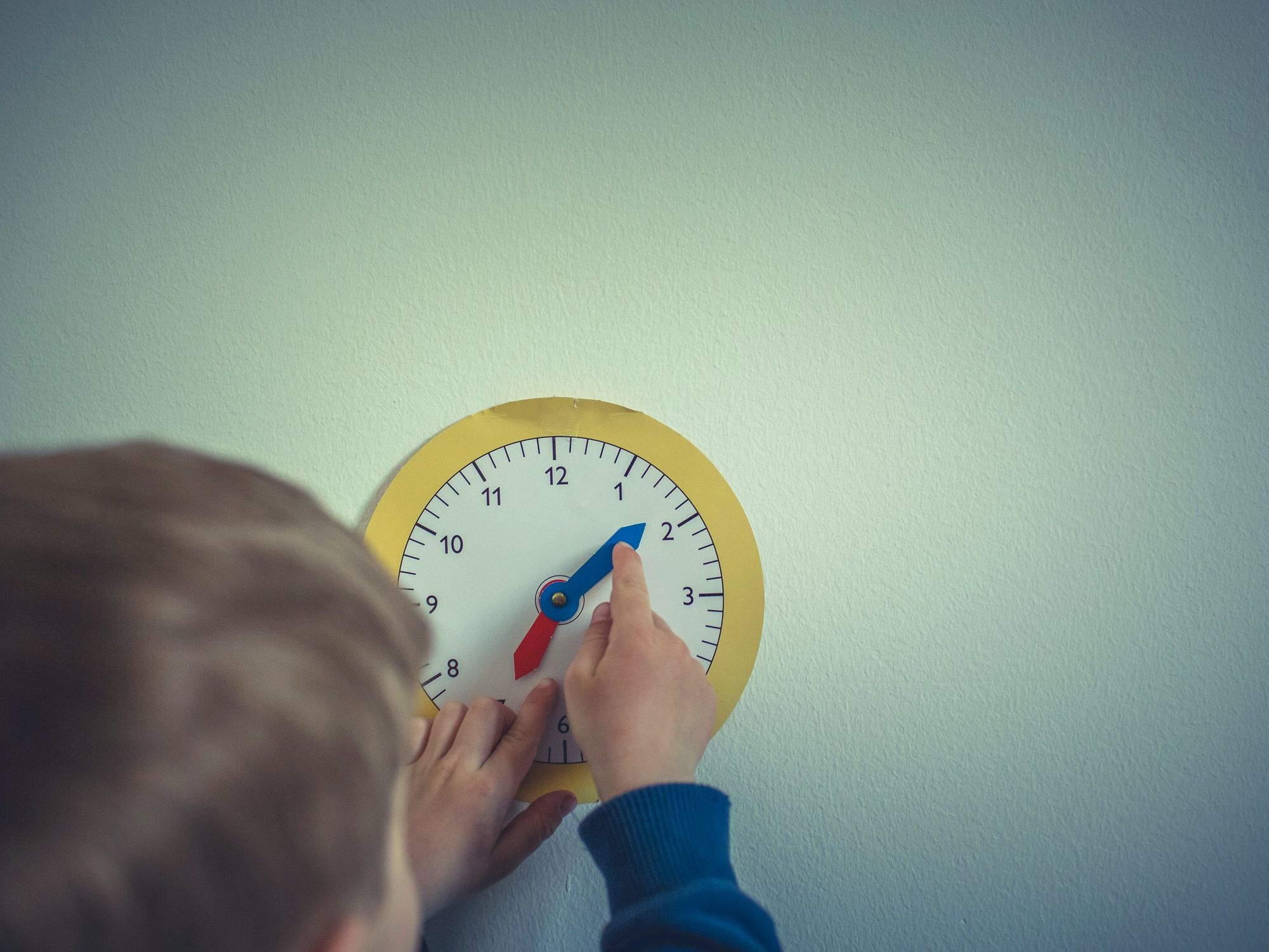 ​Child in blue long sleeve shirt holding white round analog wall clock, July 13, 2020.