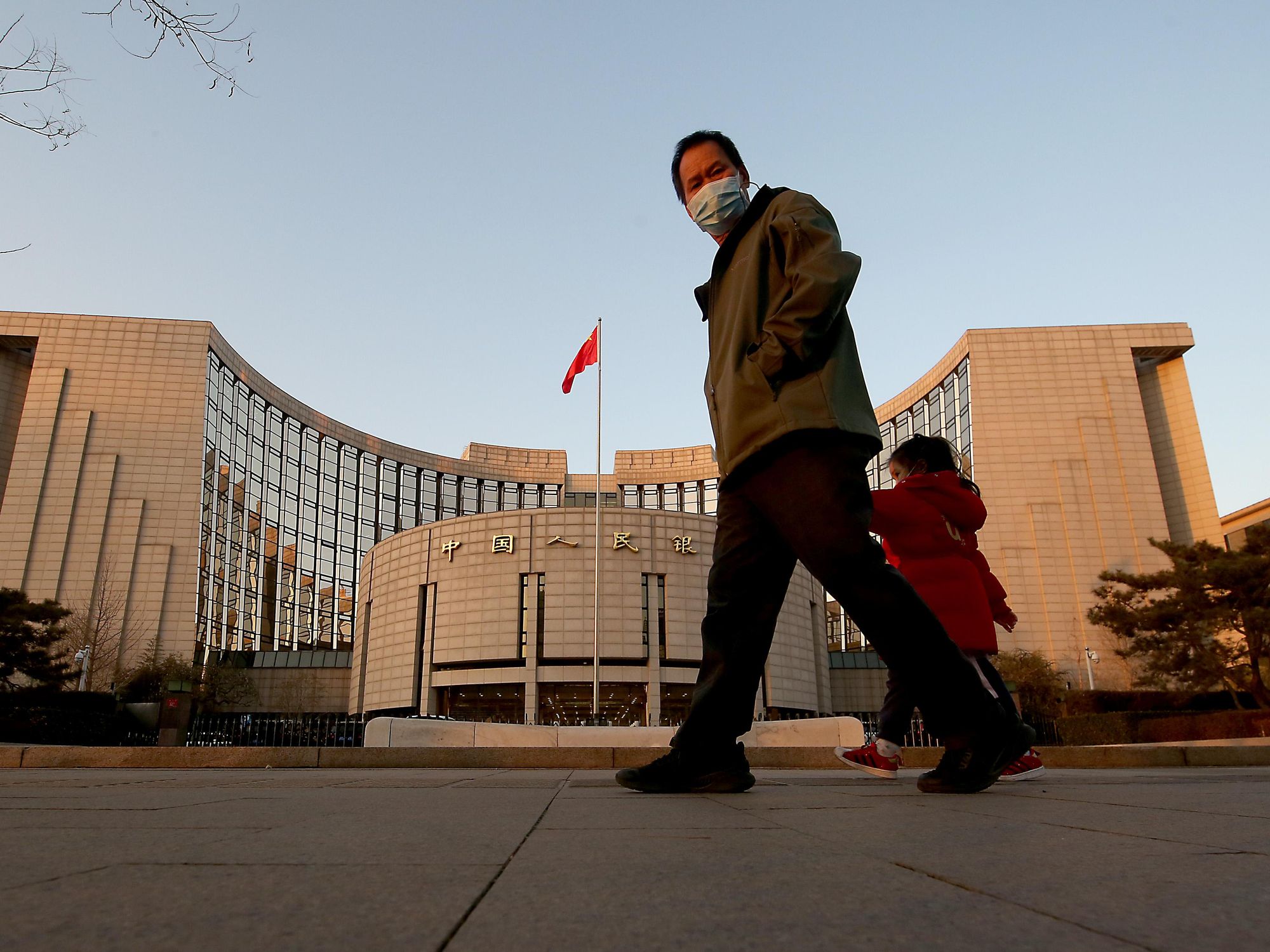 ​Chinese walk past the People's Bank of China, the country's central bank, in Beijing
