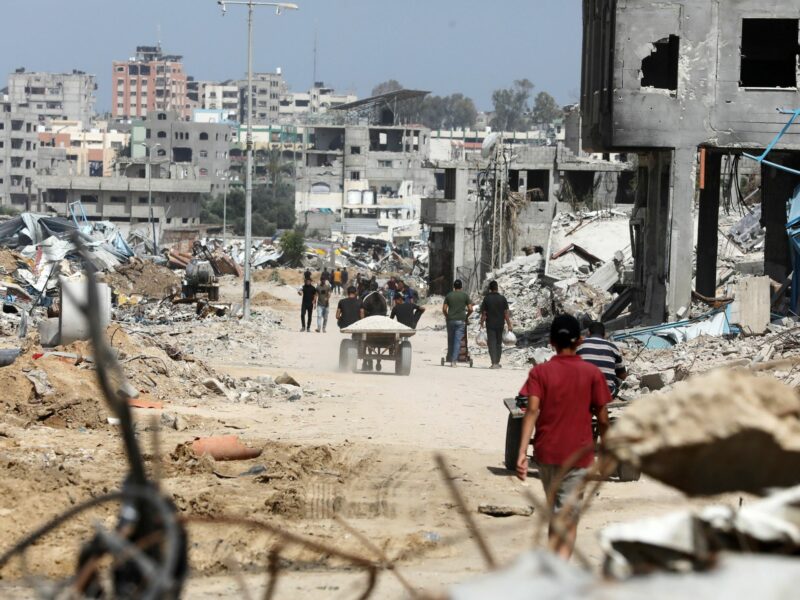 ​Displaced Palestinians walk between buildings destroyed in Israeli bombardment in Bureij refugee camp in southern Gaza.