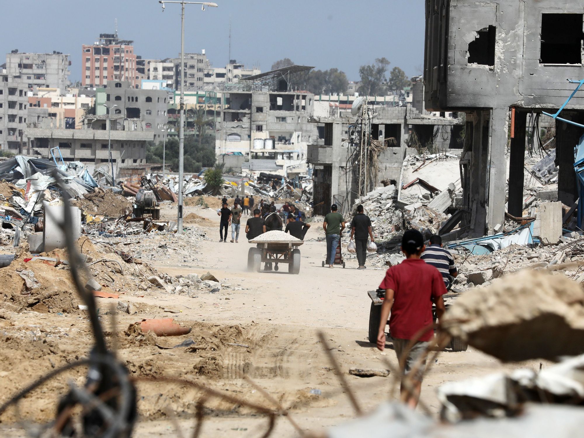​Displaced Palestinians walk between buildings destroyed in Israeli bombardment in Bureij refugee camp in southern Gaza.