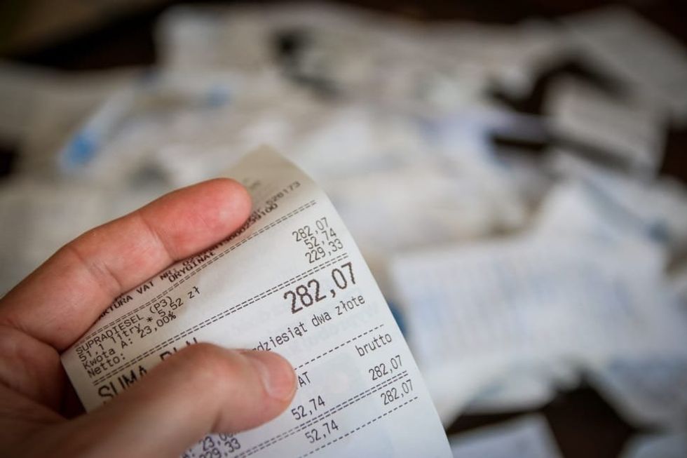 ​​A person holding a receipt totaled to 282,07.