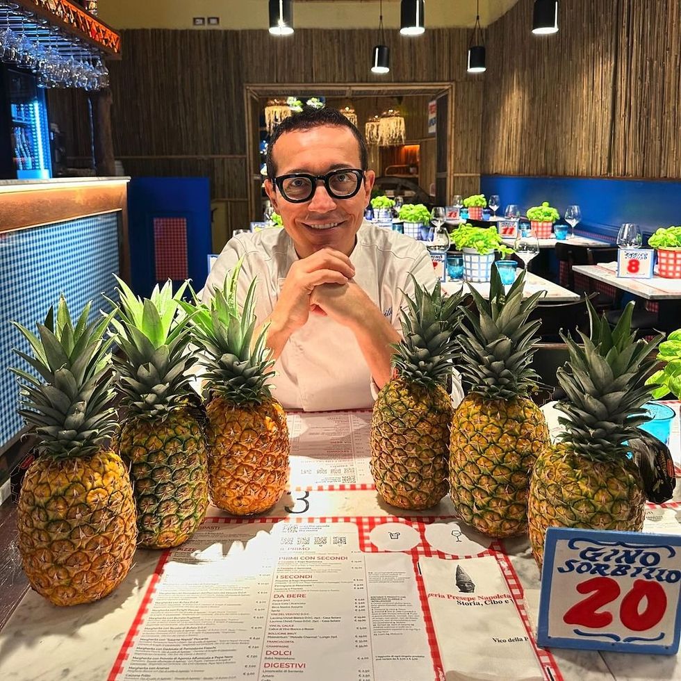 ​Gino Sorbillo sitting in front of a collection of pineapples.