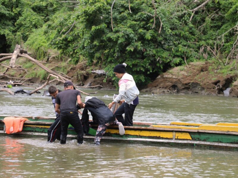 ​Group of people struggling with a boat in the water.