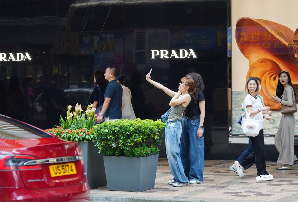 ​June 19, 2024, Hong Kong, China: Pedestrians take a selfie outside of a Prada store.