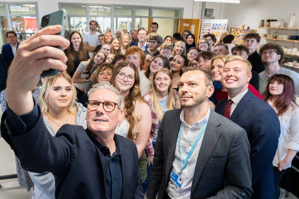 ​Keir Stramer taking a selfie with a room filled with supporters.