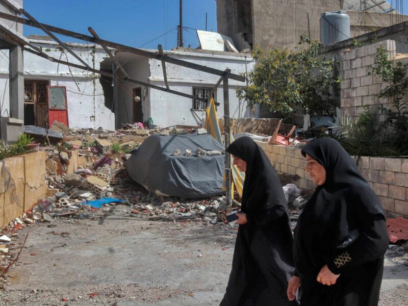 ​Lebanese women walk past a rubbled building that was hit by an overnight Israeli strike in the southern Lebanese village of Naqoura.