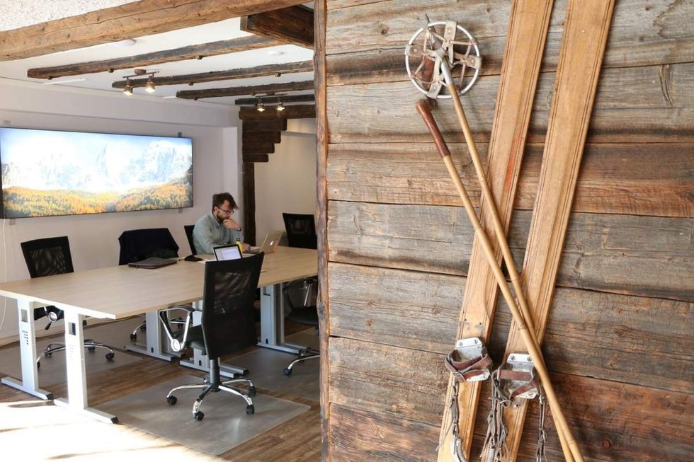 ​Man working on at a conference table with skiing equipment around the corner.