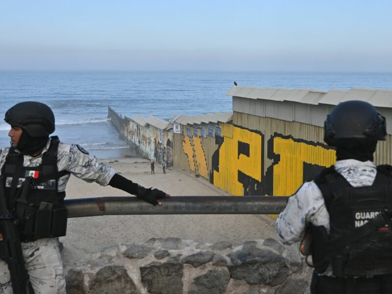 ​Members of the Mexican National Guard patrol near a new interactive mural of deported veterans at the Playas de Tijuana beach border wall.