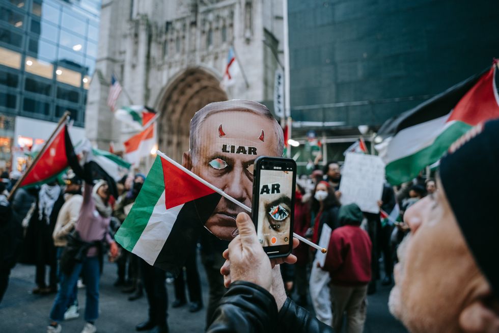 ​Palestinian protester takes a picture of a mask depicting Israel Prime Minister Netanyahu during the demonstration in New York, on Dec. 25, 2023