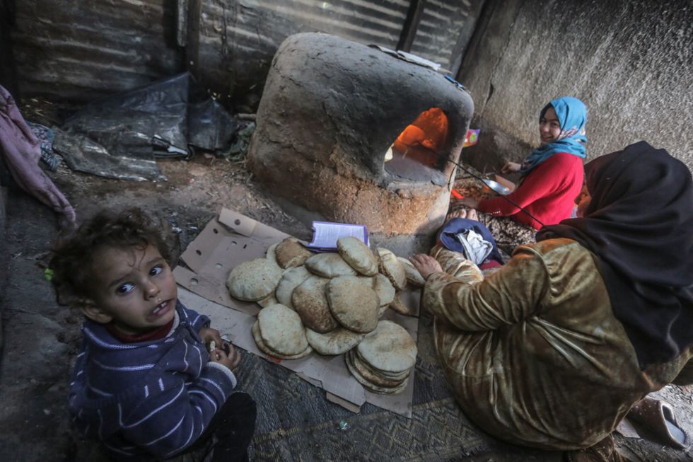 ​Palestinian refugees bake taboon bread in their temporary home during the cold weather in December in the northern Gaza Strip.