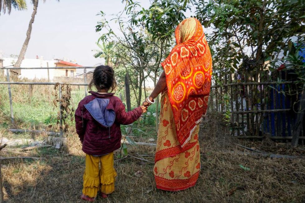 ​Paswan, a mother who asked to be identified only by her last name for fear of stigma, holds hands with her youngest daughter in their neighborhood in Sarlahi, Nepal. The woman aborted a female fetus and had heavy bleeding after.