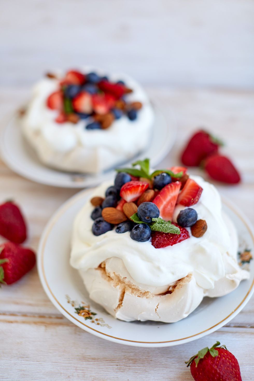 ​Pavlova dessert with strawberries and blueberries on top.