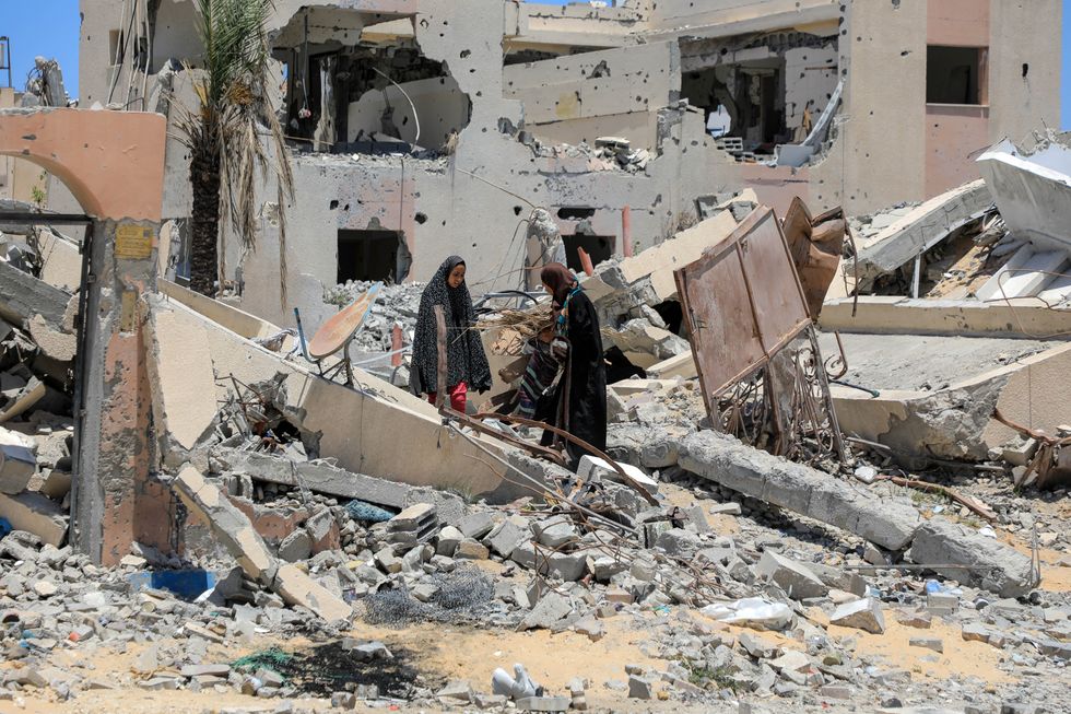 ​People collect items from the rubble of a building destroyed in Israeli strikes in the southern Gaza Strip city of Khan Younis.
