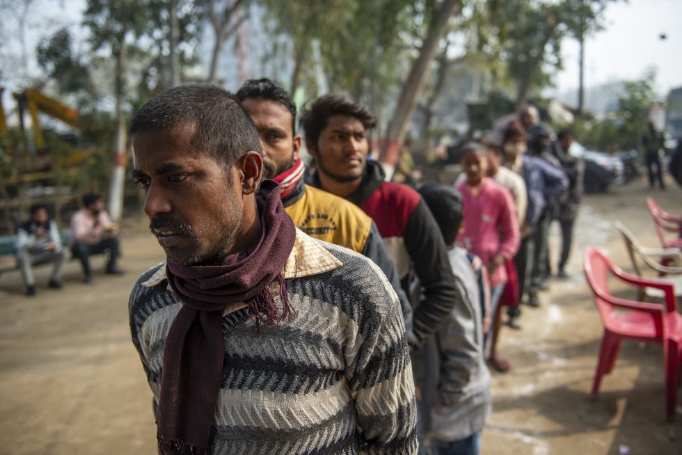 ​People queue up for food at a subsidized food center in Vashundhara, India.