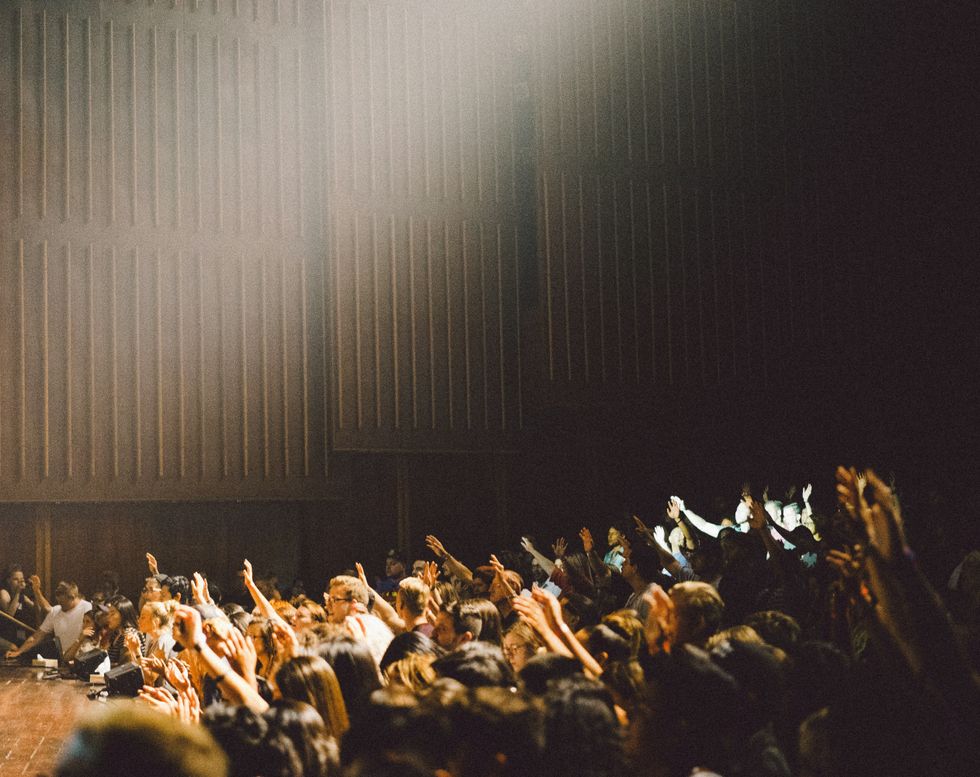 ​People raising their hands at a concert.
