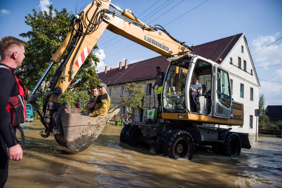 ​People traveling on a excavator in a flooded street in Lewin Brzeski.